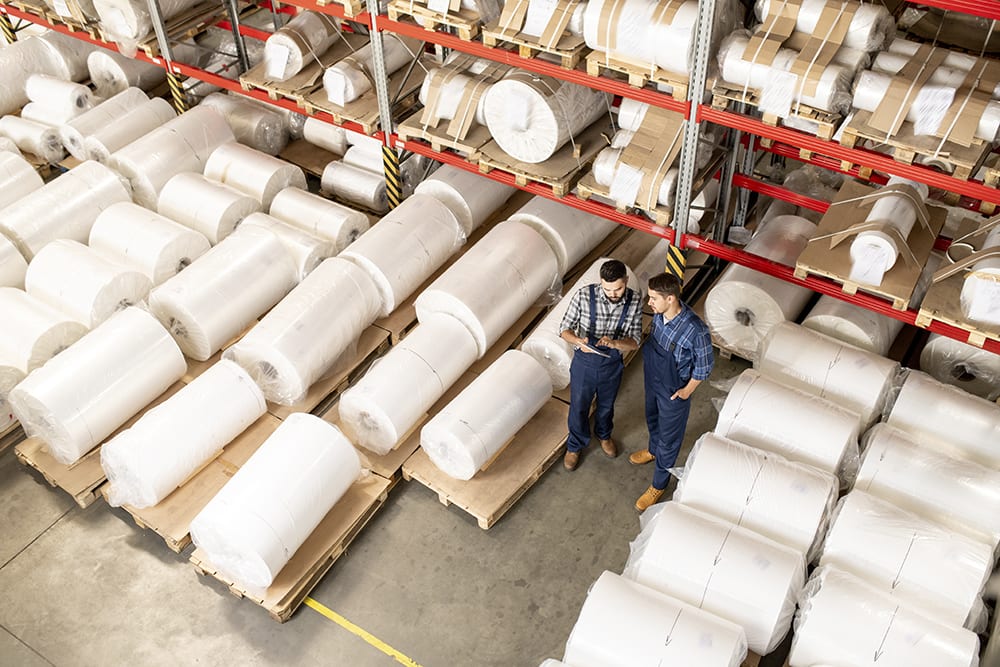 Two young engineers of large processing factory working in warehouse